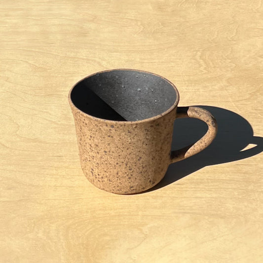 Speckled brown ceramic mug on a wooden surface